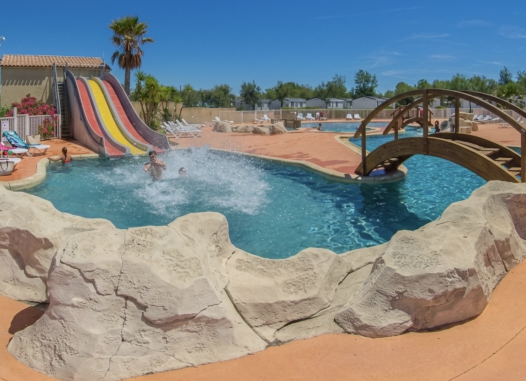 Piscine lagon avec toboggans colorés et pont en bois — Domaine de Saint Maurice